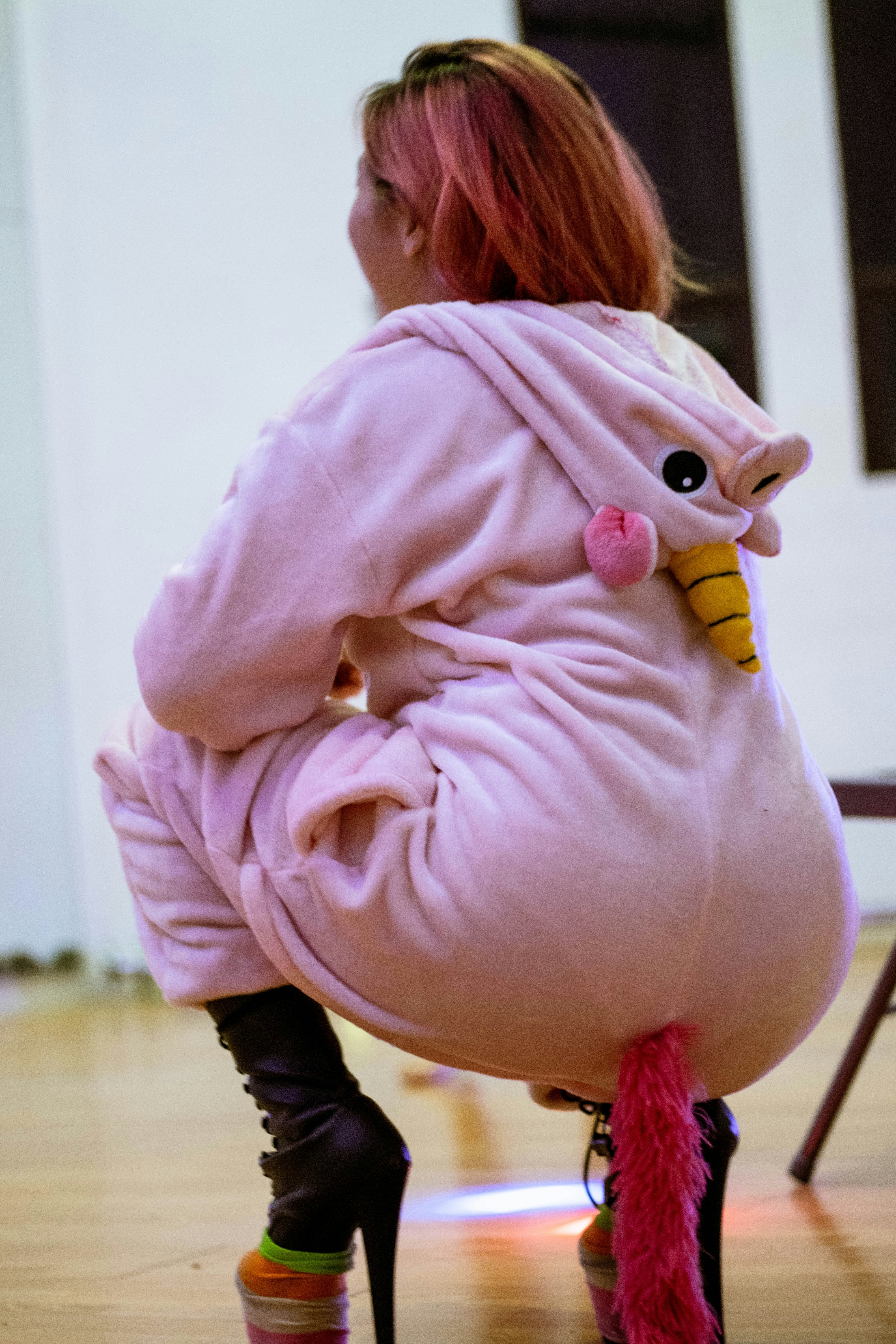 girl in pink jacket and black pants sitting on brown wooden floor
