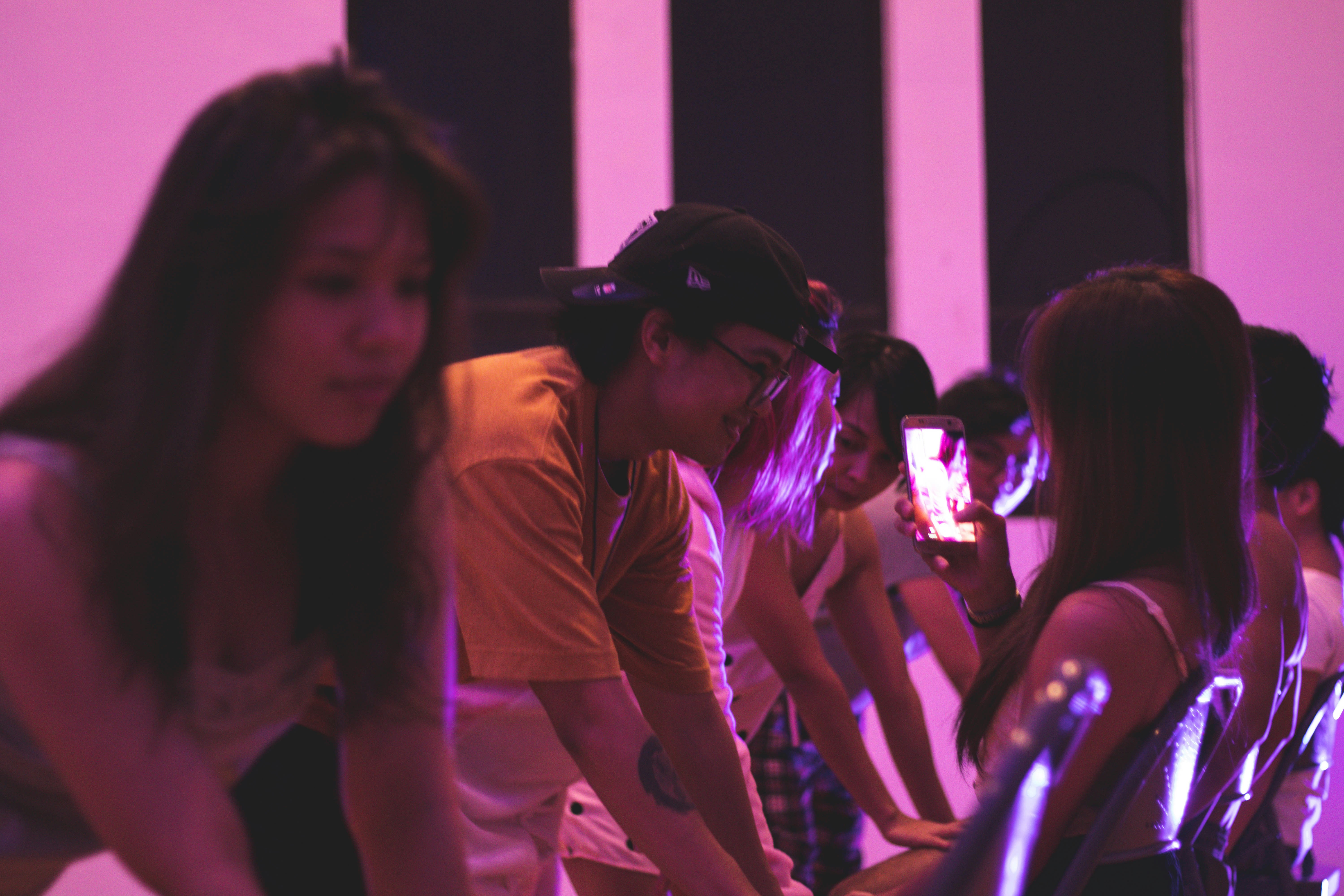 Riders in an indoor cycling class under pink lighting