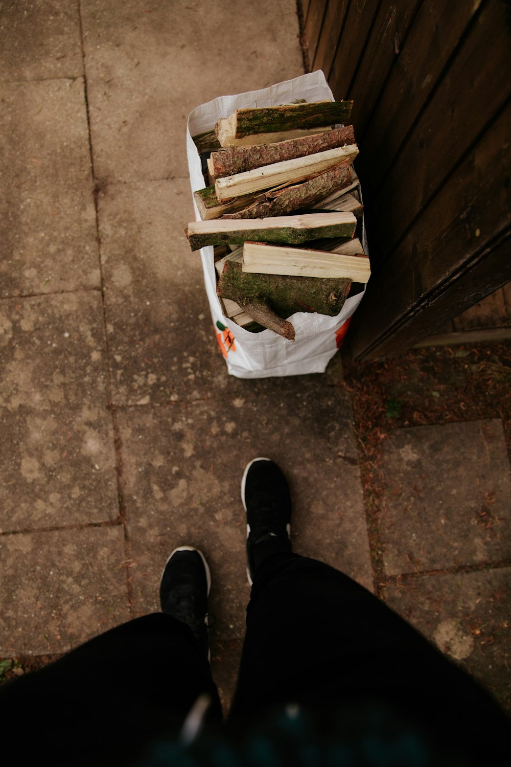 person in black pants and black shoes standing on brown wooden pallet