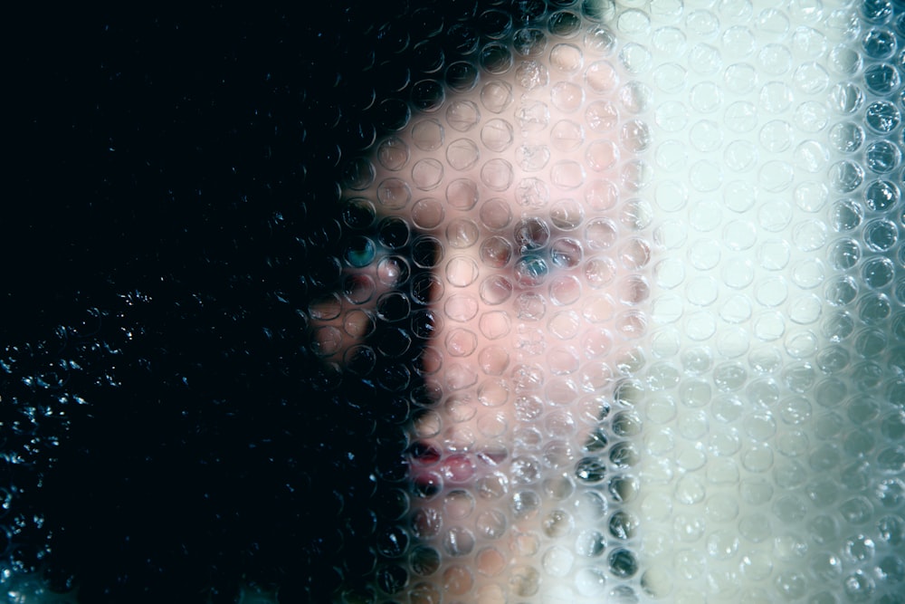 a woman looking through a window with bubbles on it