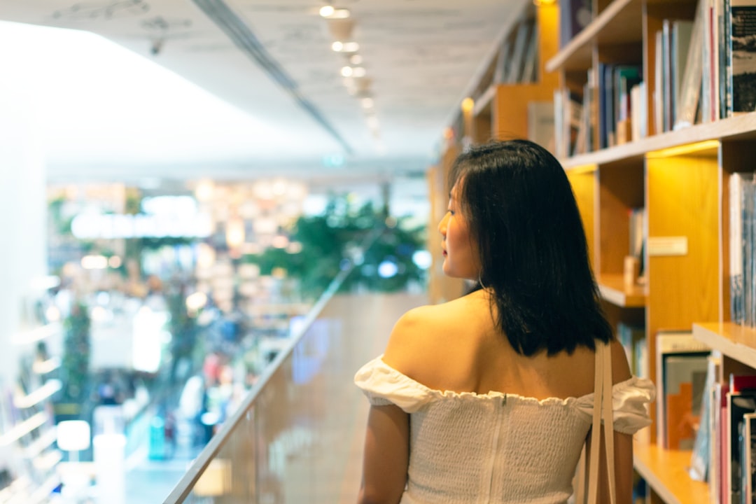 woman in white off shoulder dress standing near glass wall