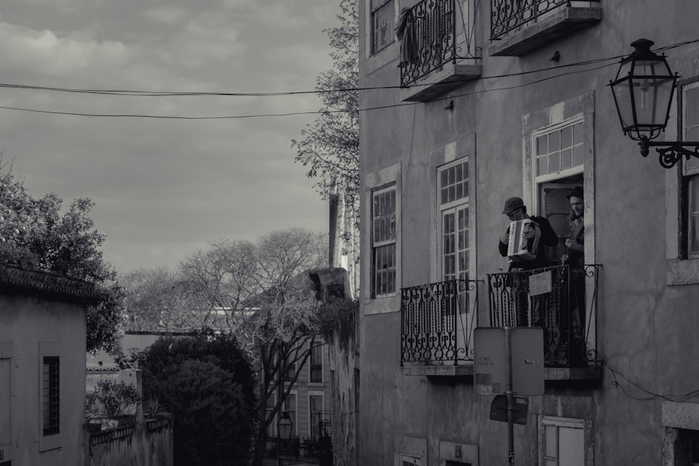 grayscale photo of man in black jacket standing on balcony