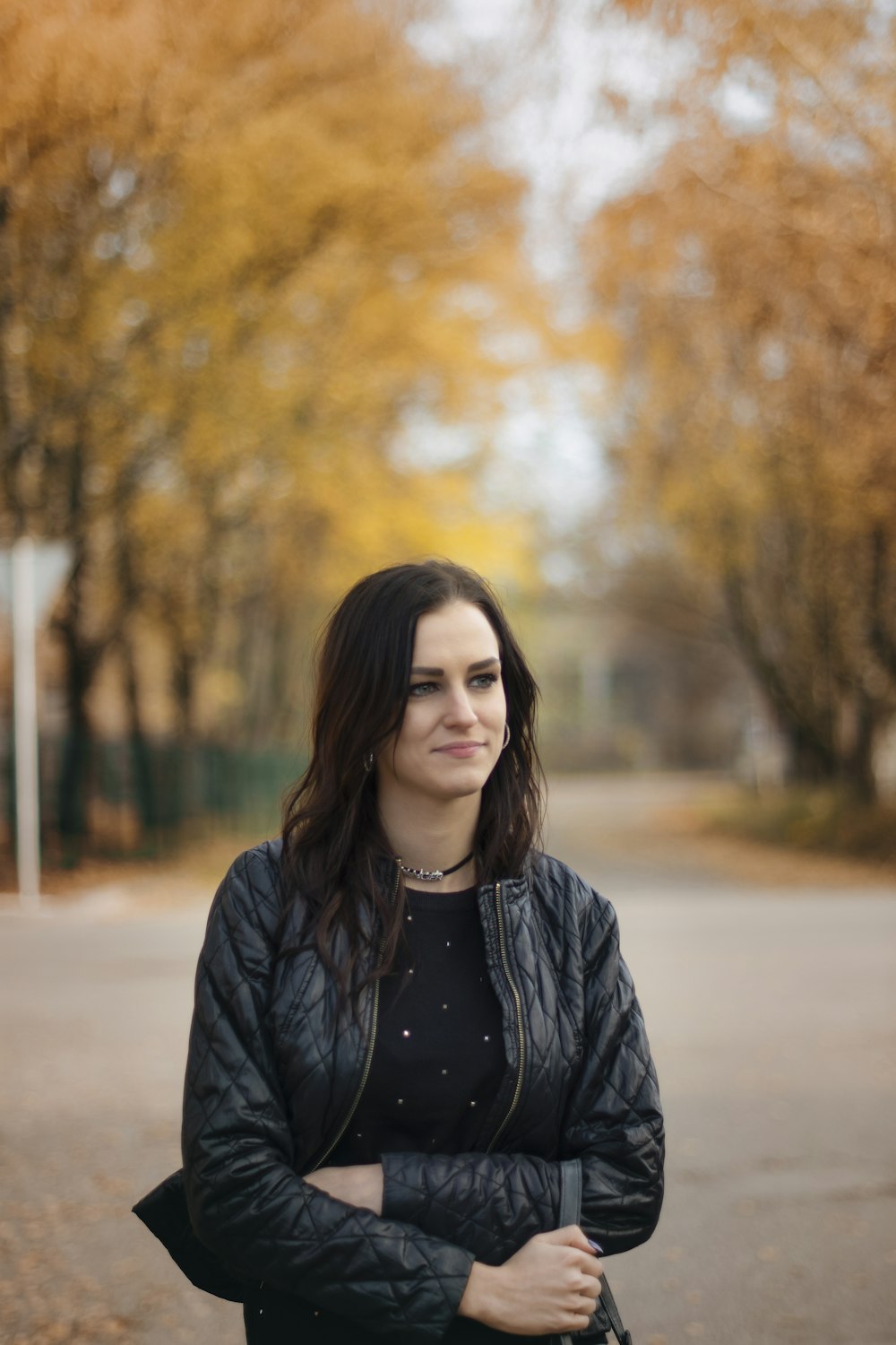 woman in black jacket standing on road during daytime