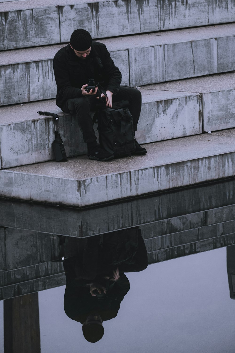 man in black jacket sitting on concrete stairs