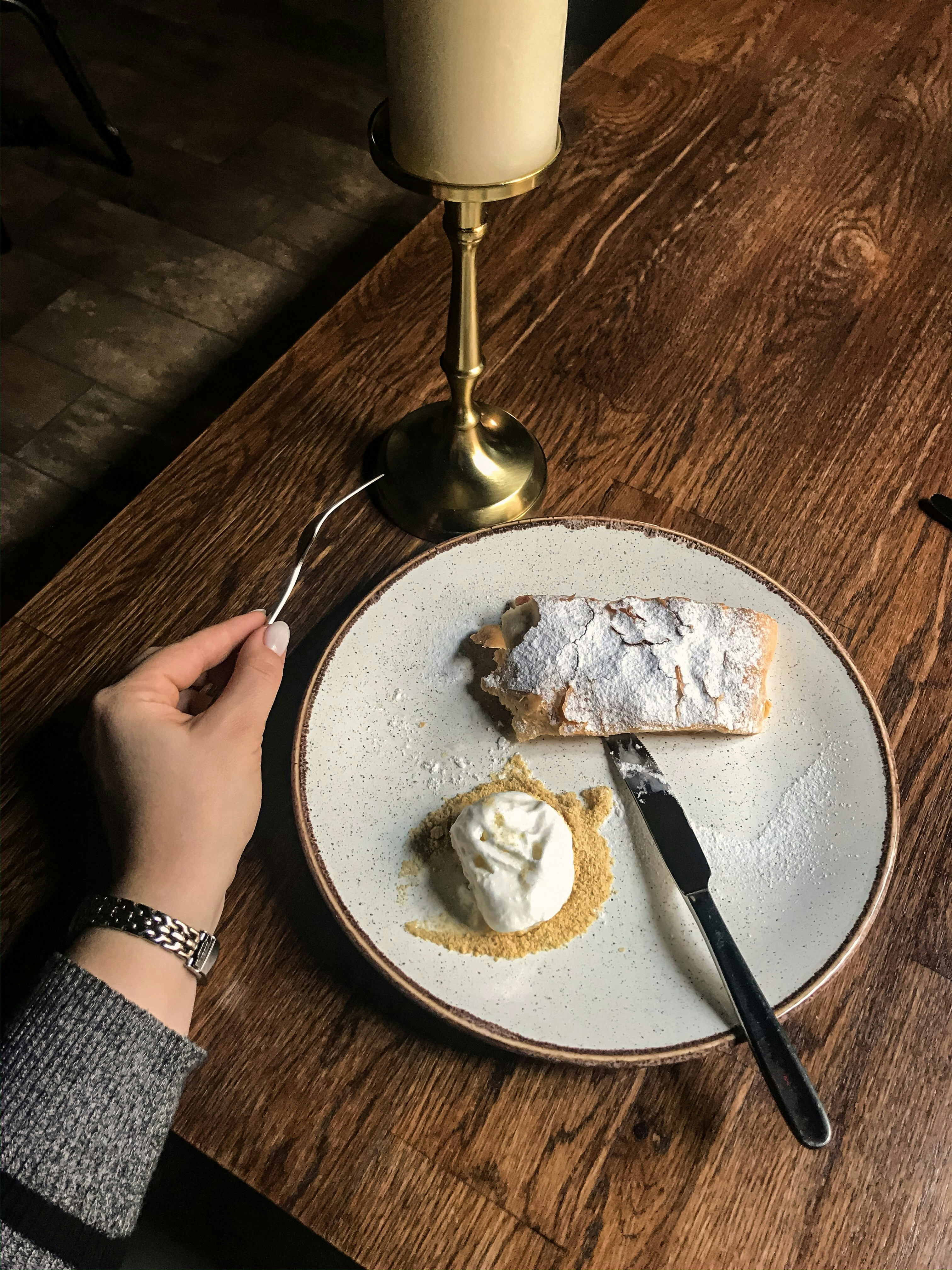 person holding stainless steel spoon and fork on white ceramic plate