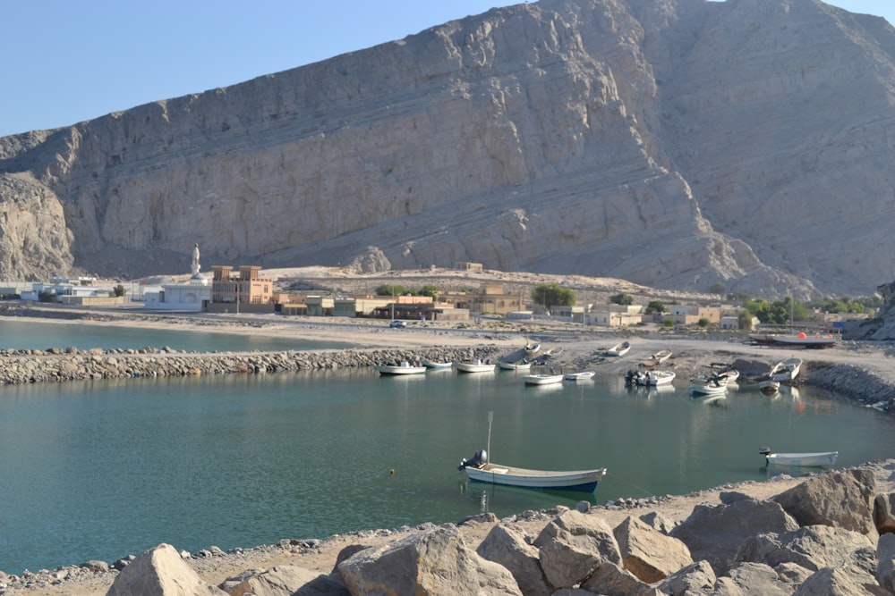 blue and white boat on body of water near mountain during daytime