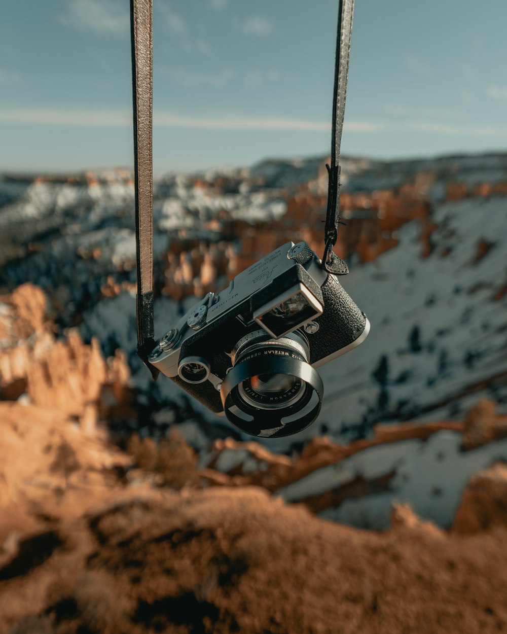 Fotocamera DSLR nera e argento appesa a una corda nera