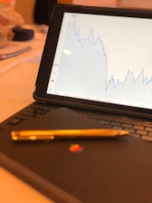 A close-up of a hand tapping on a tablet displaying graphs.