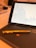 A tablet displaying a line graph with fluctuating data labeled as Tesla is positioned on a keyboard cover. In the foreground, a gold pen lies on top of the cover with a colorful logo visible.