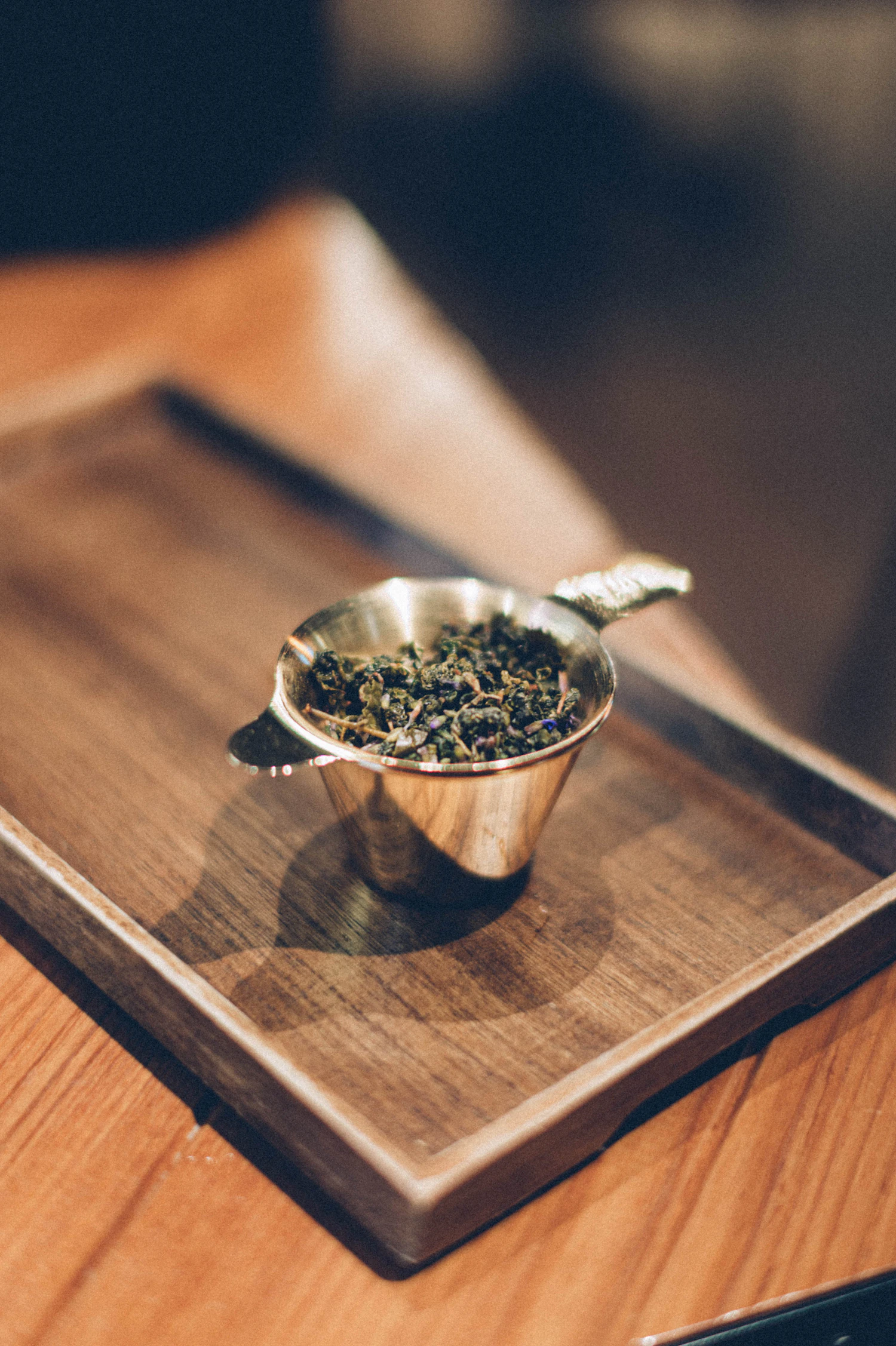 A steel measuring scoop levelled off with dark leaf on a wooden board