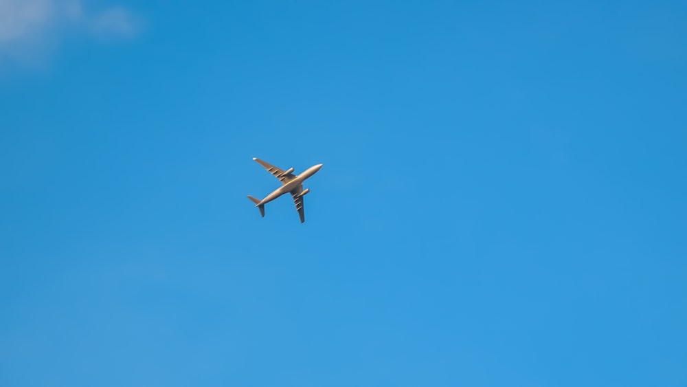 昼間の青空の下、空中に浮かぶ白い飛行機