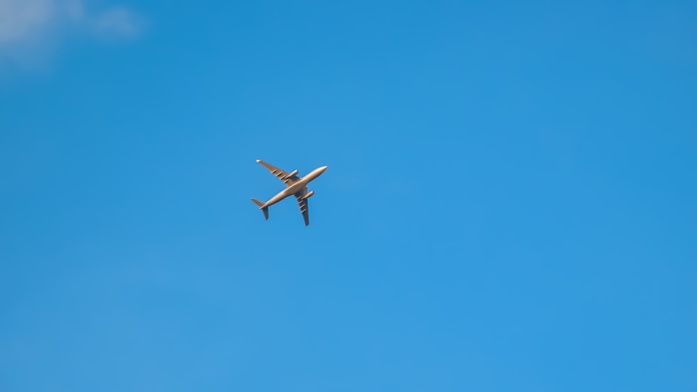 white airplane in mid air under blue sky during daytime