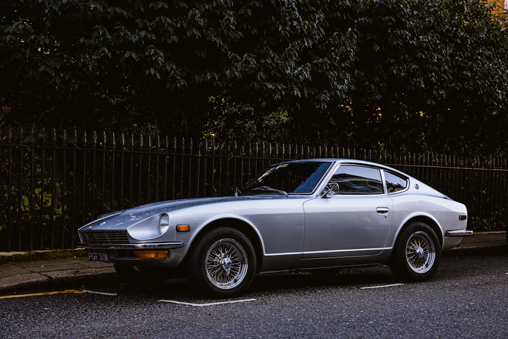 Silver Coupé tagsüber in der Nähe von Bäumen geparkt