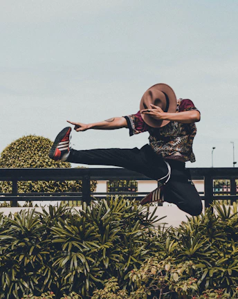 Dynamic shot of a Black man mid-motion, expressing freedom and culture against a pastel green backdrop.