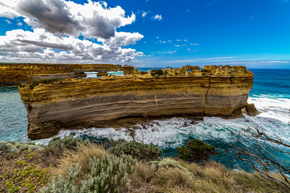 brown rock formation near body of water under blue sky during daytime