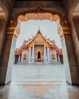 The Wat Benchamabophit temple framed by an ornate marble archway in Bangkok, Thailand