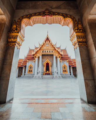 The Wat Benchamabophit temple framed by an ornate marble archway in Bangkok, Thailand
