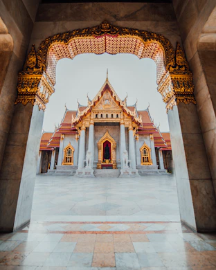 The Wat Benchamabophit temple framed by an ornate marble archway in Bangkok, Thailand