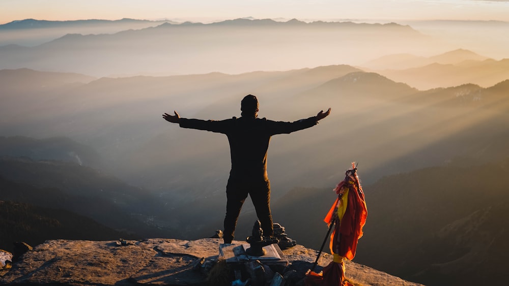 man in black jacket standing on rock formation during daytime