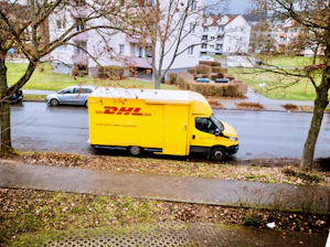 yellow and white box truck parked on sidewalk during daytime