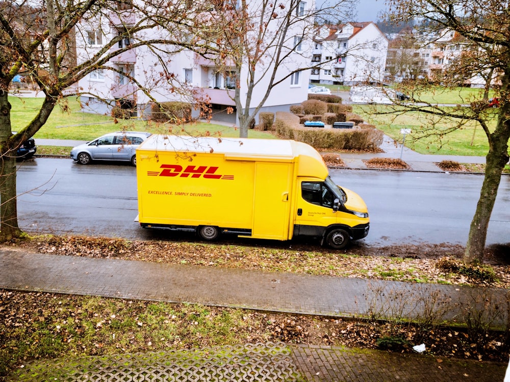 yellow and white box truck parked on sidewalk during daytime