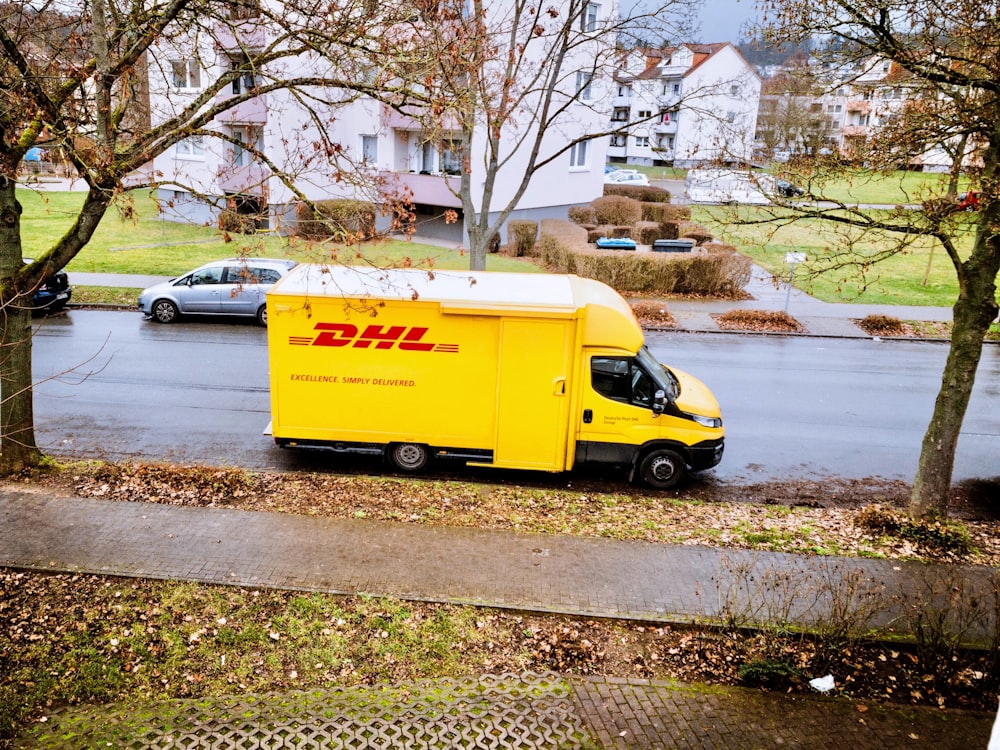 caminhão de caixa amarela e branca estacionado na calçada durante o dia