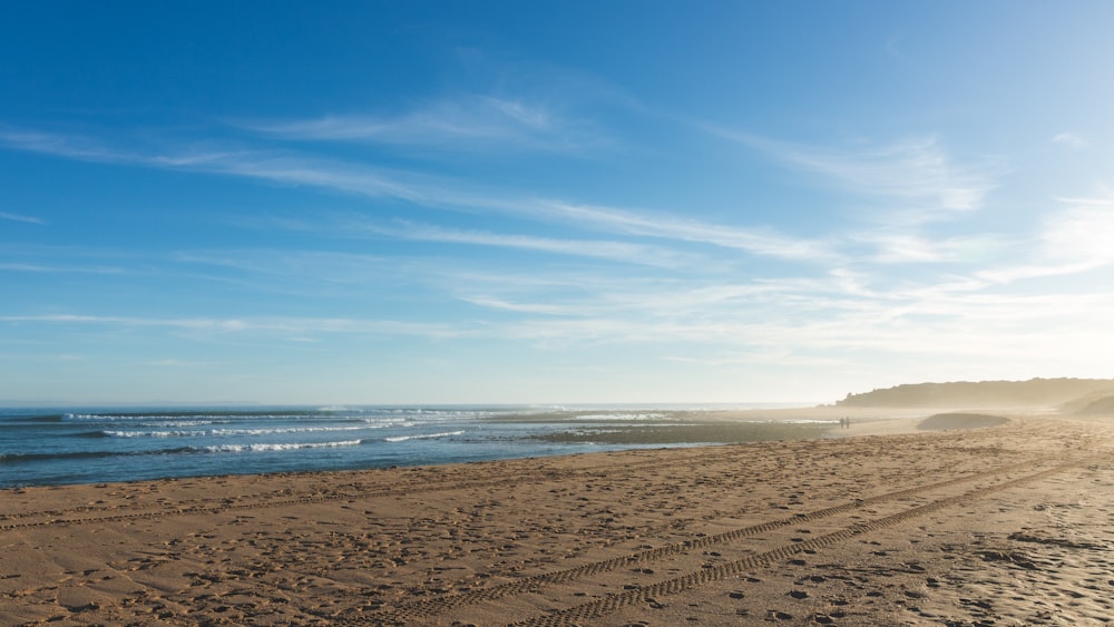 brown sand near body of water during daytime