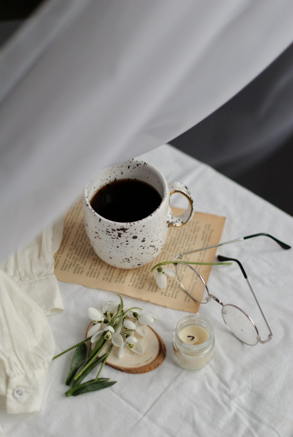 white ceramic mug on brown wooden coaster beside white flowers