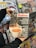 A person holding a magazine titled 'Kahve' shows a close-up of a coffee machine pouring espresso into a white cup. It features articles about franchising coffee shops and various coffee-related topics. In the background, there is a display of various other magazines on shelves.