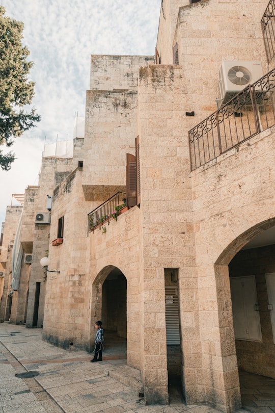 people walking on sidewalk near brown concrete building during daytime in Jerusalem Israel