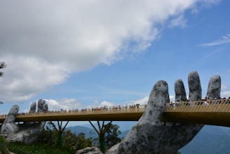 Golden Bridge held by giant stone hands at Ba Na Hills under a bright blue sky.