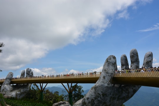 brown wooden bridge under blue sky during daytime in Sun World Bà Nà Hills Vietnam
