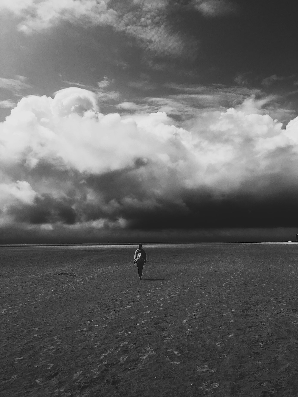 grayscale photo of woman walking on beach
