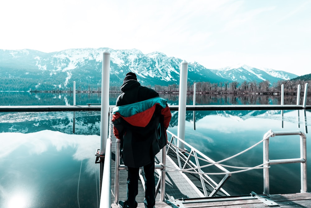 man in green hoodie standing on white metal bridge during daytime