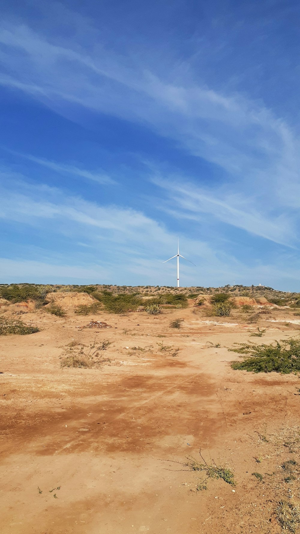 white wind turbine on brown field under blue sky during daytime