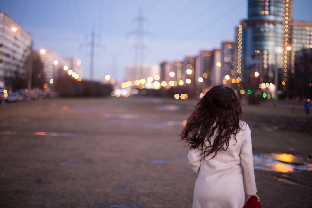 woman in white long sleeve shirt standing on sidewalk during night time