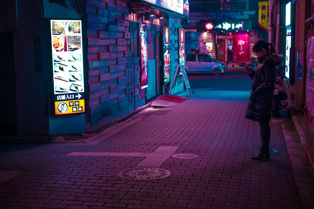 man in red jacket walking on sidewalk during nighttime