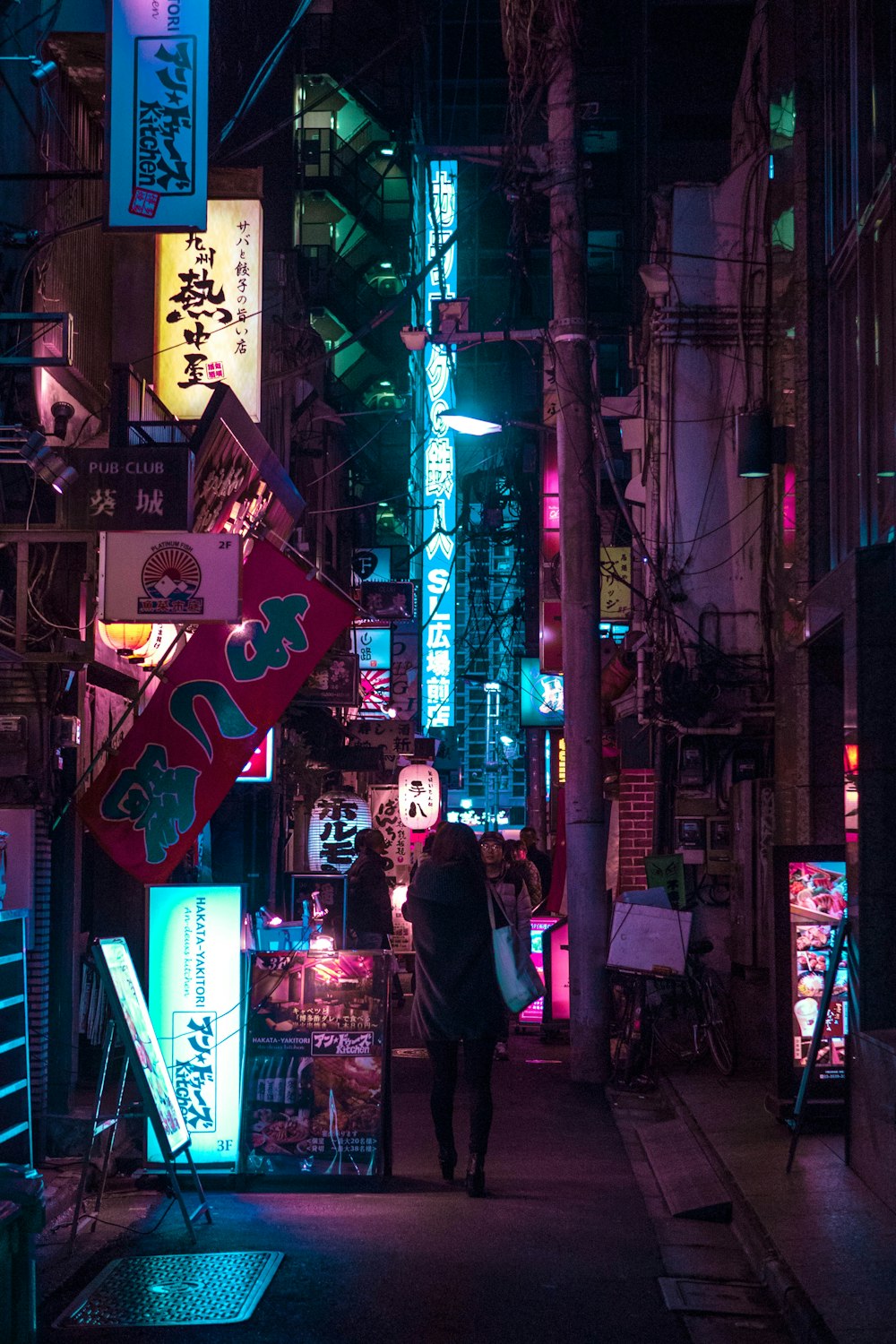 man in black coat standing beside store during night time