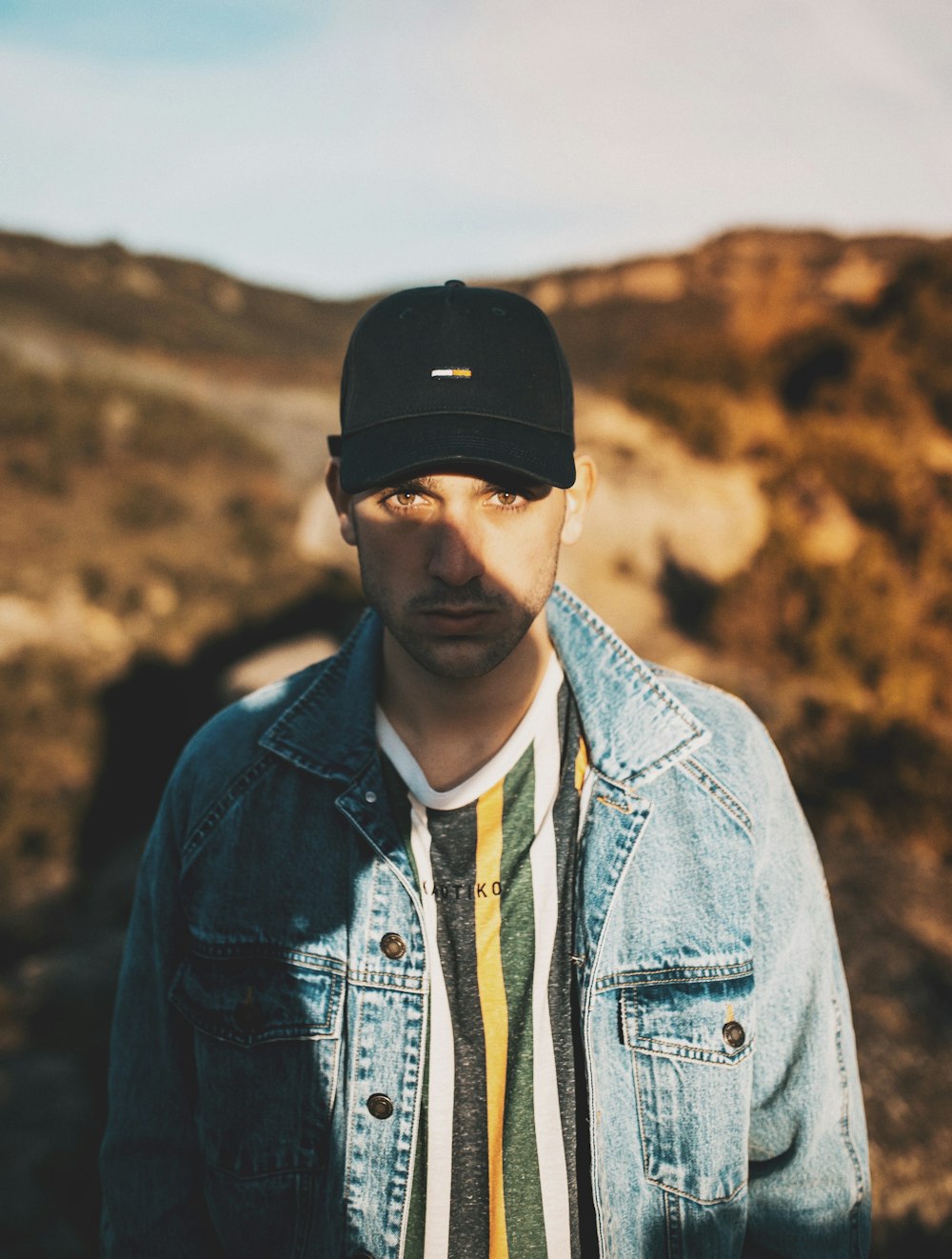 man in blue denim jacket wearing black cap