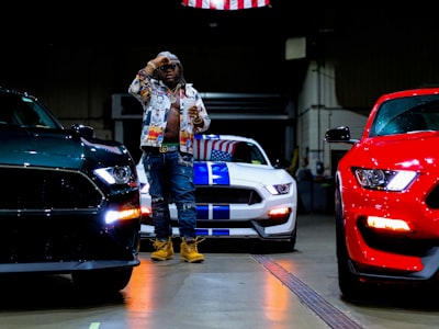 woman in white and black jacket standing beside red car patriots teams background