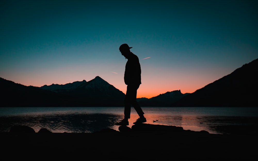 silhouette of man standing on seashore during night time