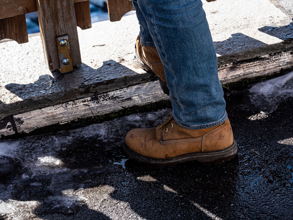 person in blue denim jeans and brown leather boots