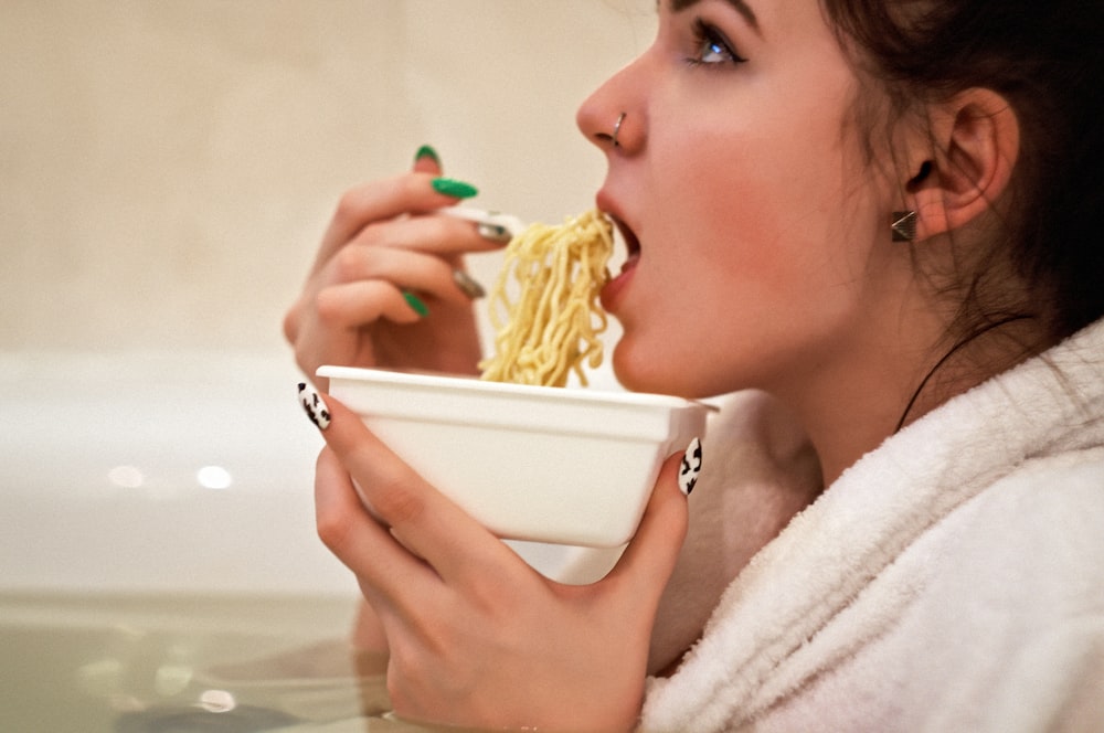 woman holding white ceramic bowl with yellow pasta