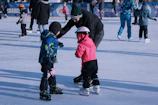 Smiling instructor helping a child perfect their skating posture on smooth pavement