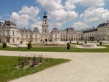 Historic palace exterior surrounded by lush gardens under clear skies.