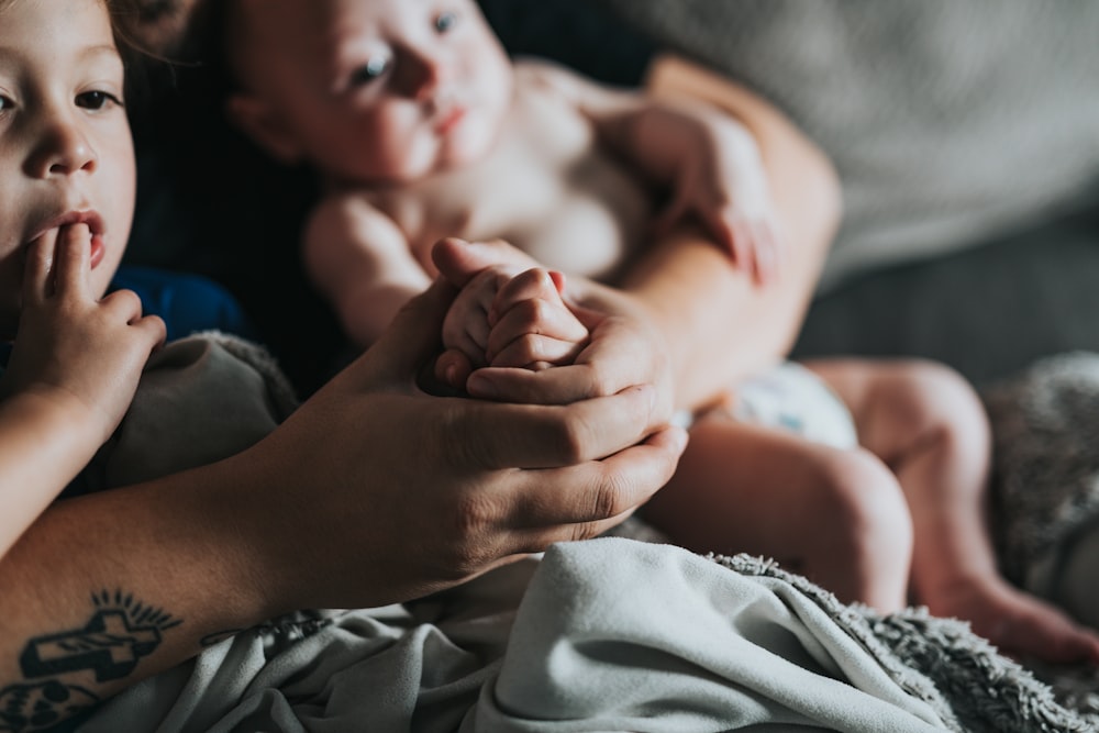 person holding baby on gray textile