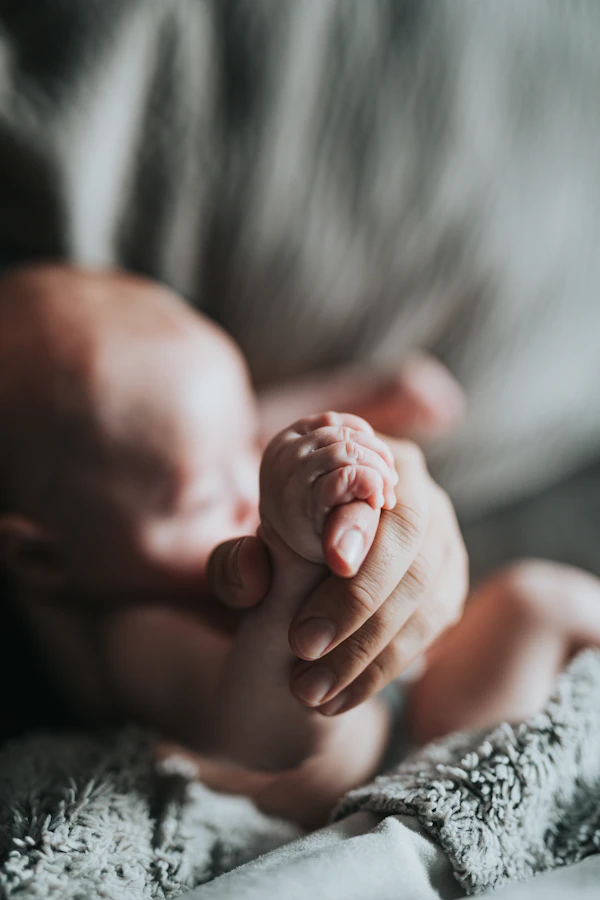 Adult hand holding tiny newborn baby hand