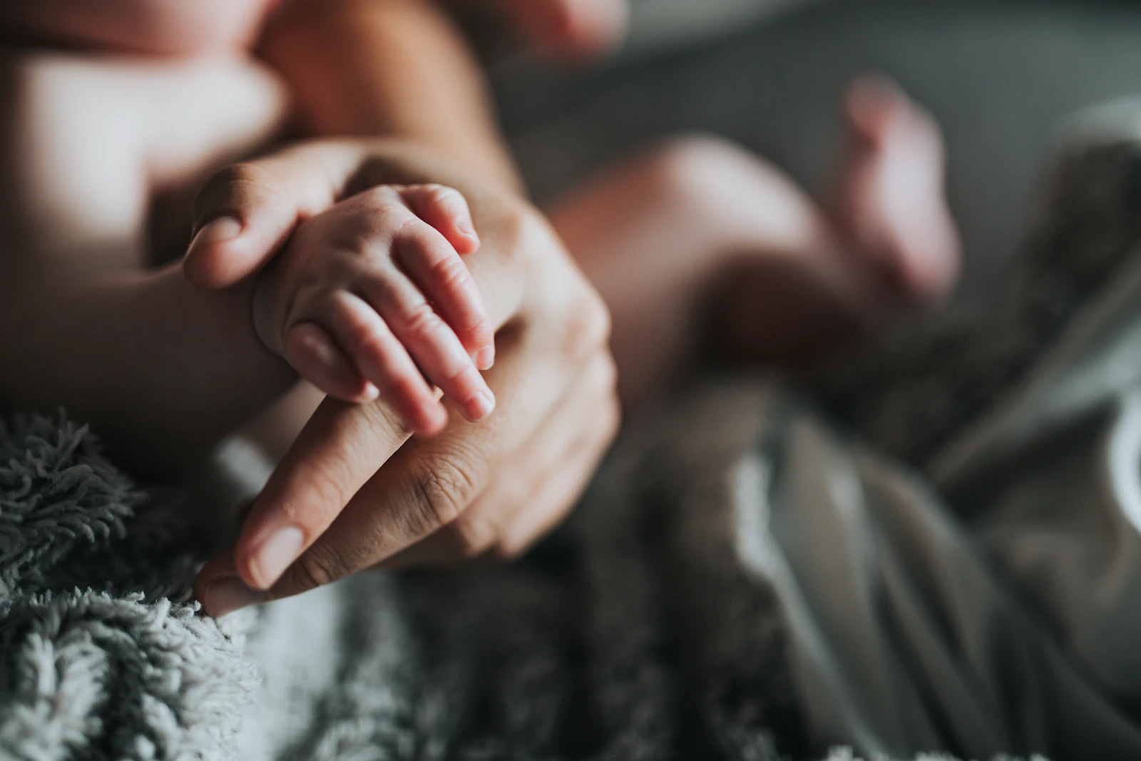 Unas manos adultas sostienen los pequeños pies de un recién nacido