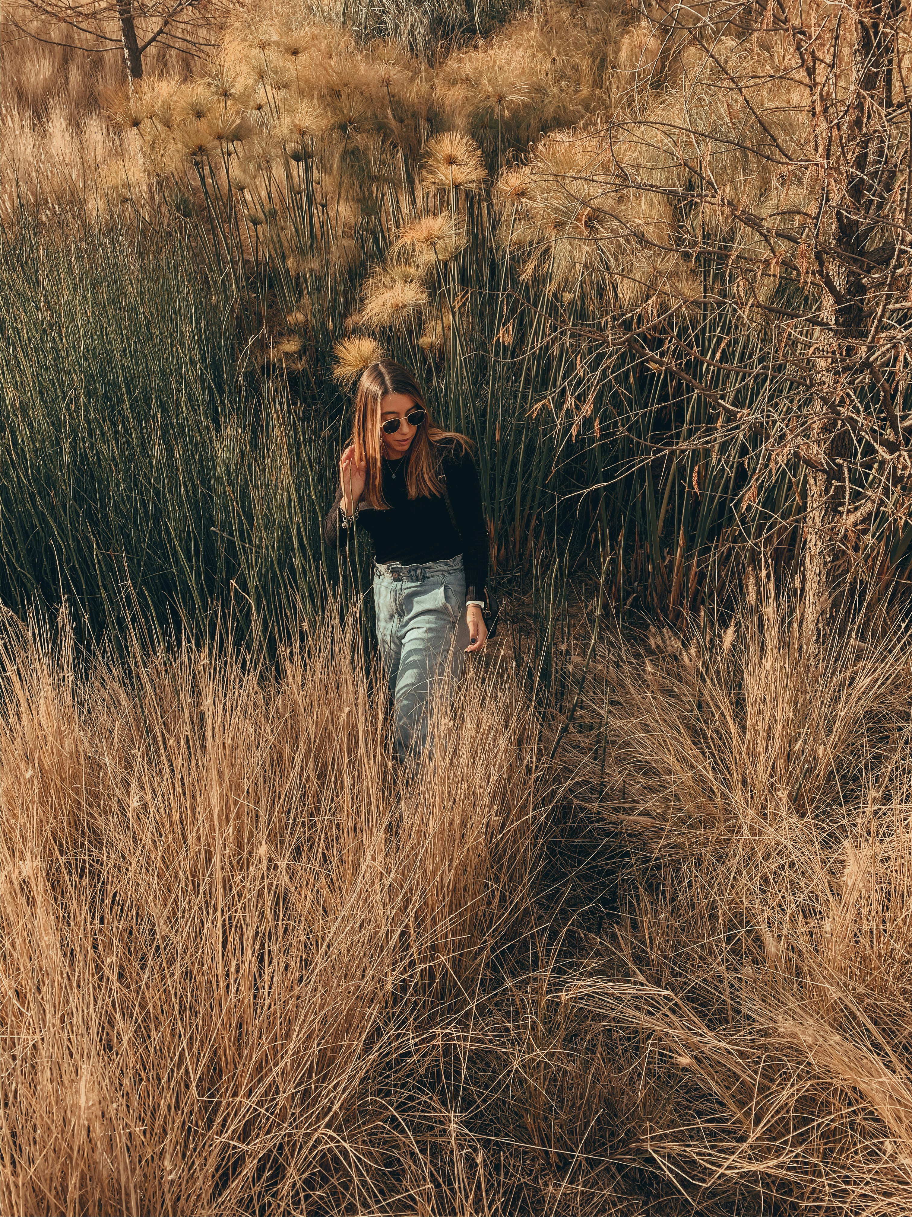 woman in black long sleeve shirt and blue denim jeans standing on brown grass field during