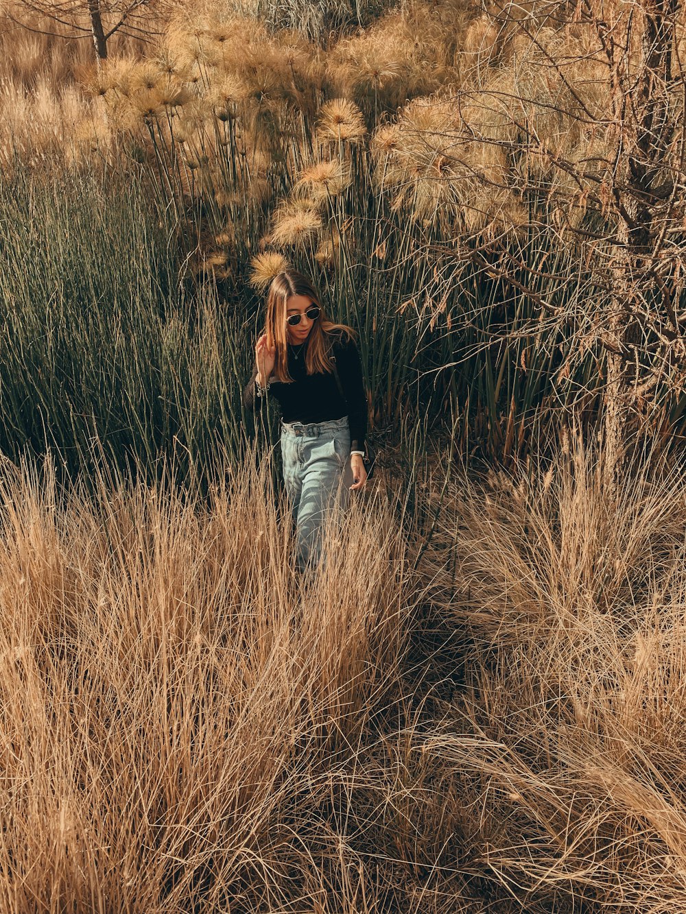 woman in black long sleeve shirt and blue denim jeans standing on brown grass field during